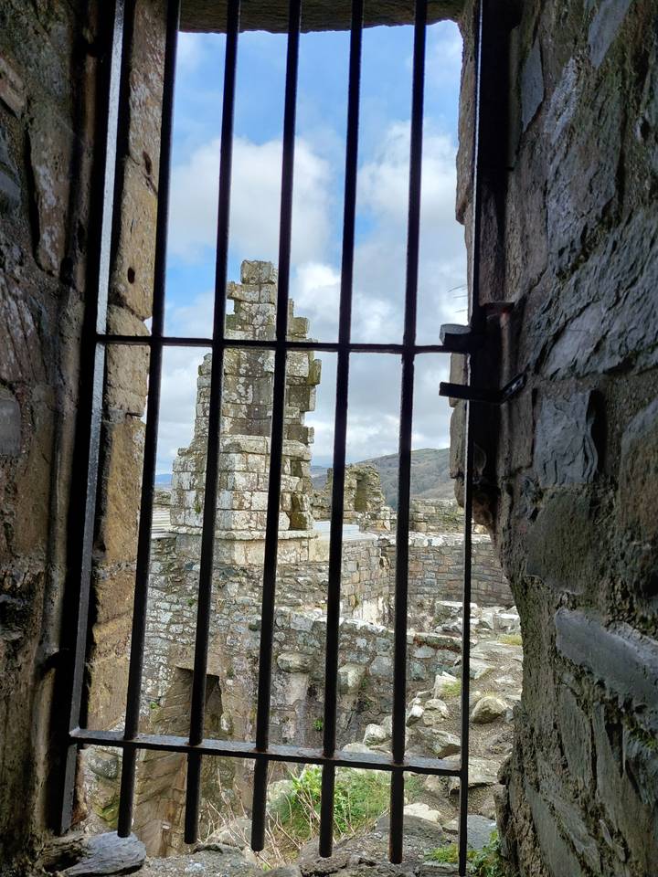 Vue de ruines historiques à travers une fenêtre à barreaux.
