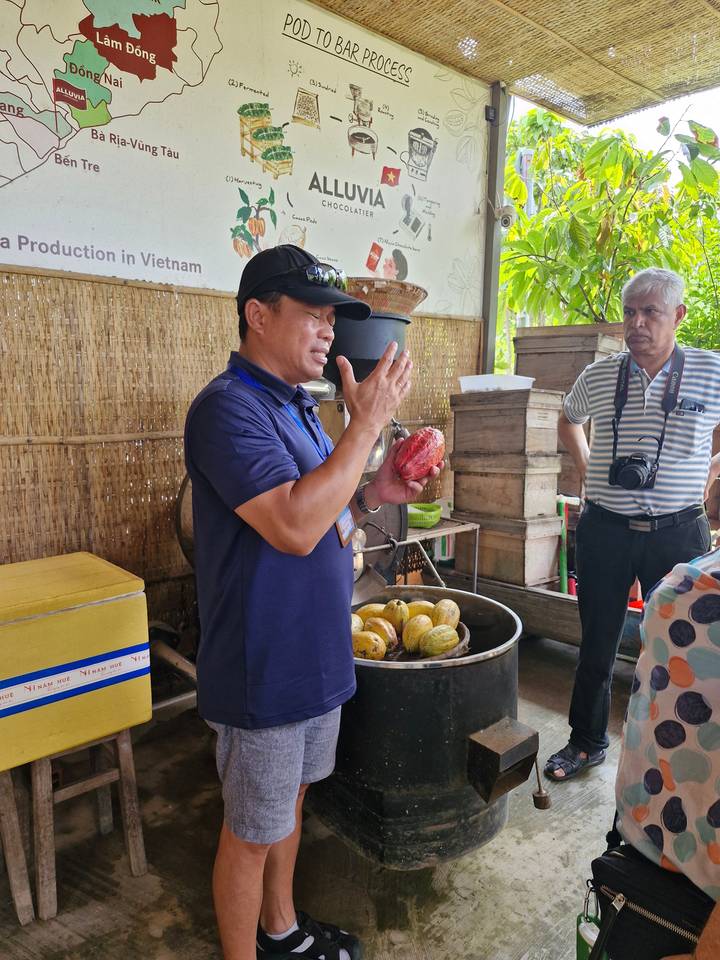Personne tenant un fruit dans un contexte de marché.