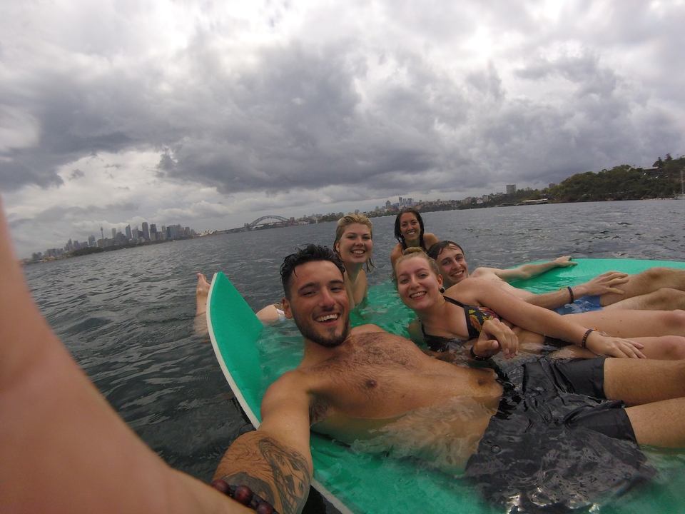 Group of people on paddleboards in the sea with cityscape in the background.