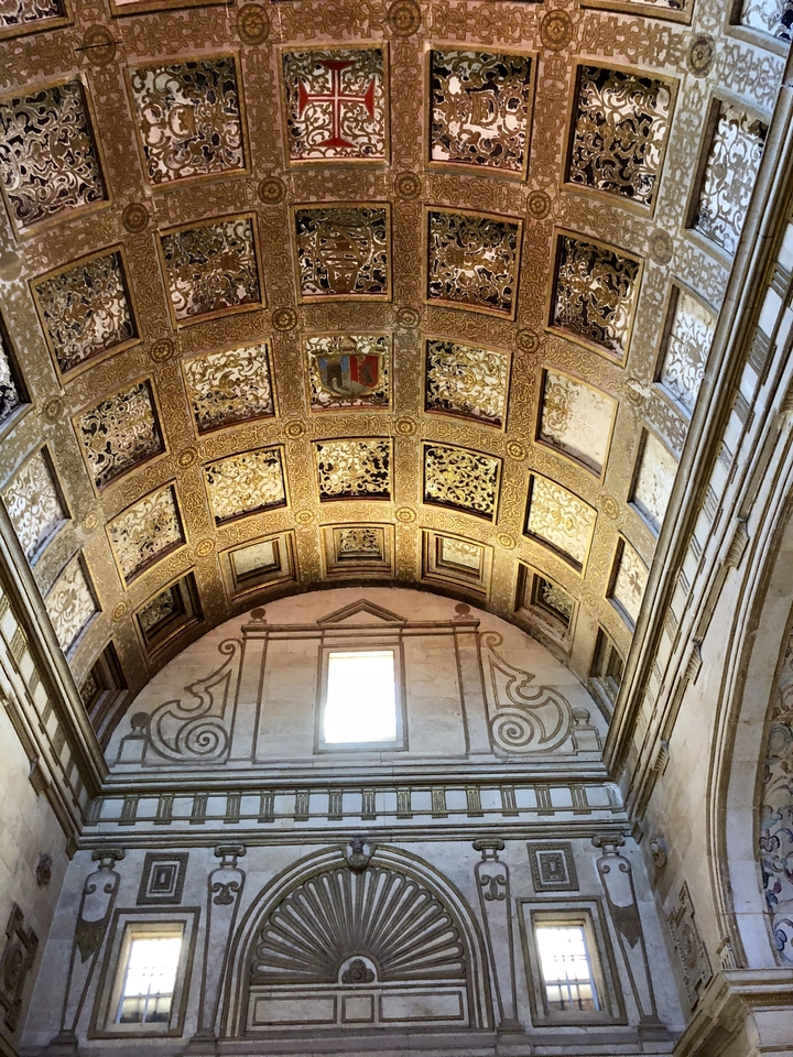 Plafond décoratif avec des motifs complexes et un blason.