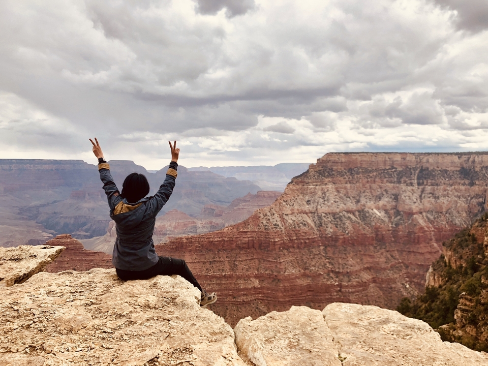 Personne levant les bras au Grand Canyon avec des vues panoramiques.