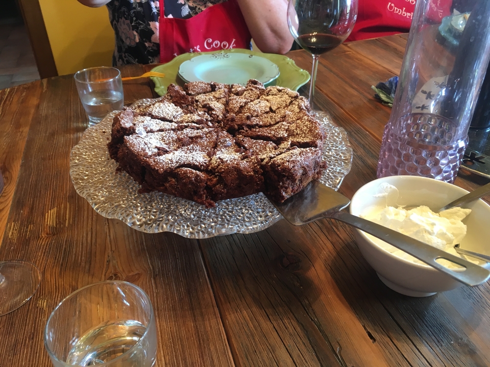 Gâteau au chocolat sur un plat de service avec de la crème à côté.
