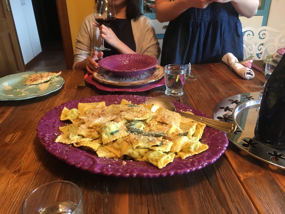 Table de salle à manger avec un plat de pâtes et des personnes qui savourent un repas.