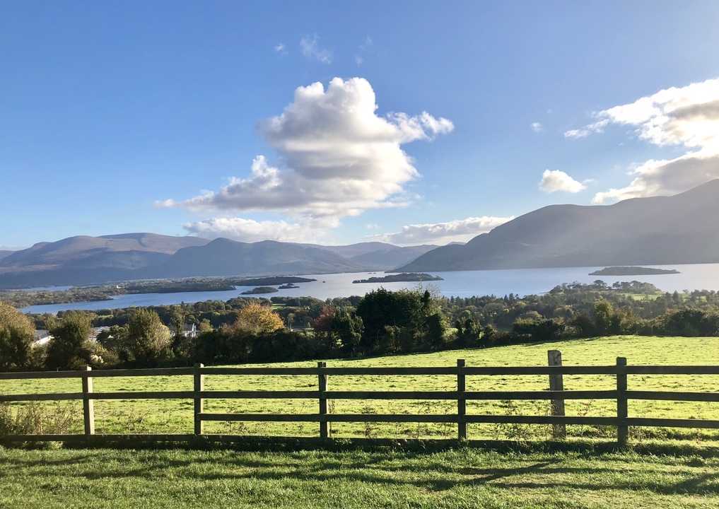 Scenic view of a lake surrounded by mountains and fields.