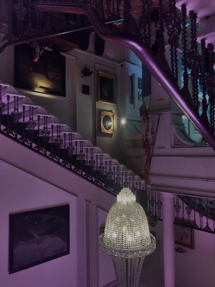 Mur de galerie avec escalier orné et œuvres d'art.