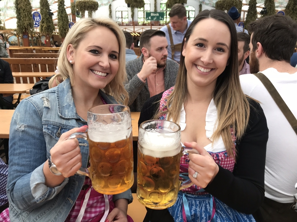Deux femmes tenant de grandes chopes de bière et souriant.