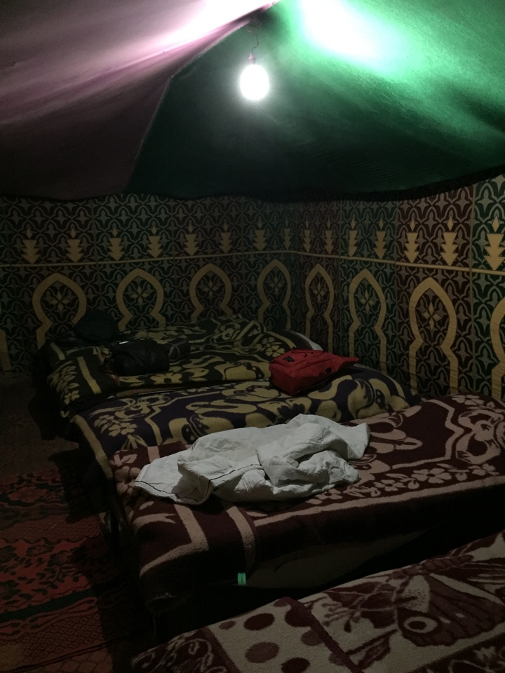 Chambre faiblement éclairée avec plusieurs lits et des motifs muraux ornementés.