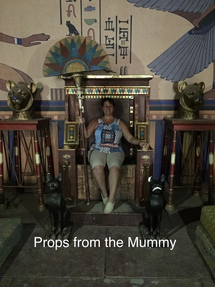 Personne assise sur un trône orné entourée de statues d'animaux.