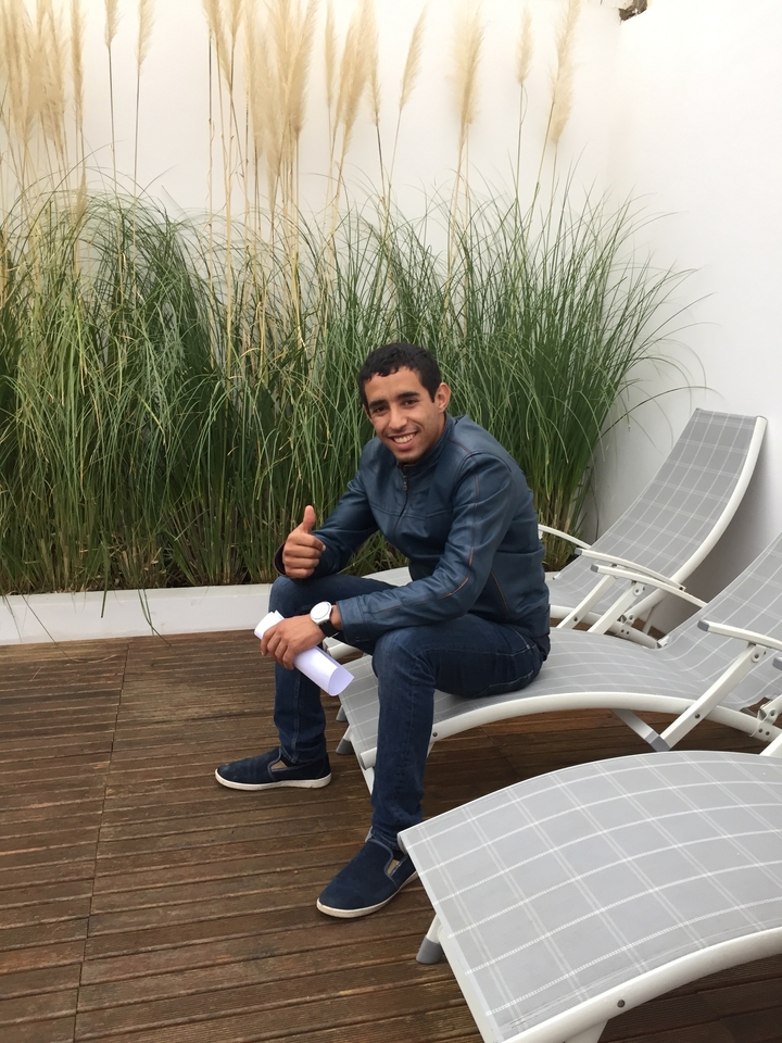 Homme souriant assis sur une chaise longue, faisant un signe de pouce levé.