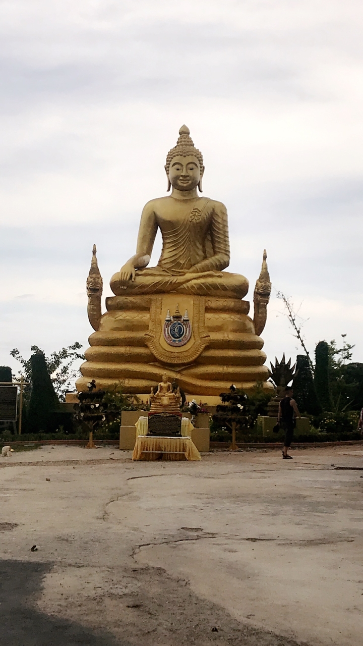 Statue dorée de Bouddha assis sur un piédestal décoré.