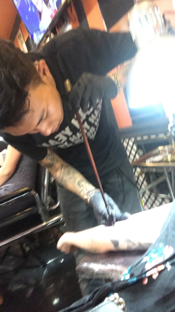 Personne avec des tatouages travaillant sur un projet artisanal.