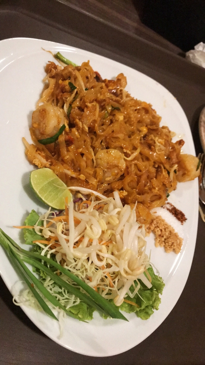 Plat thaïlandais avec des nouilles, des crevettes et du citron vert dans une assiette.