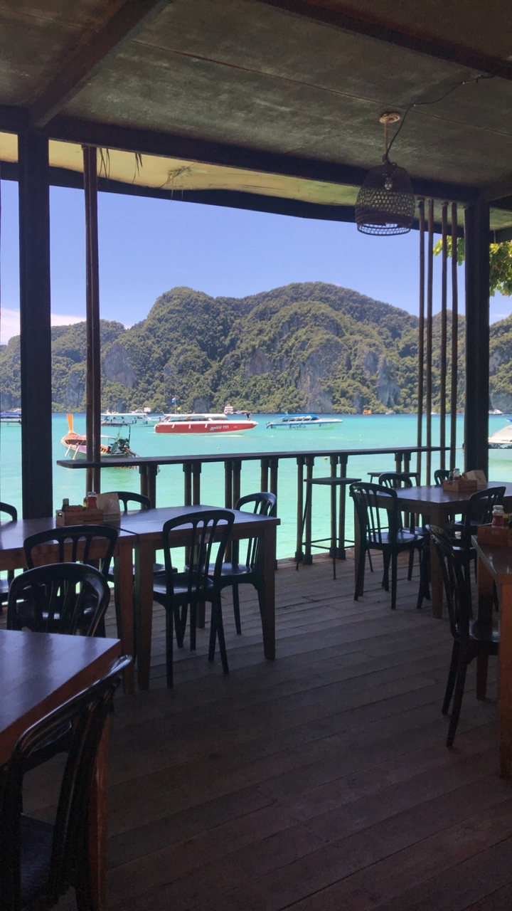 Vue panoramique depuis un restaurant donnant sur des bateaux sur une eau bleue.