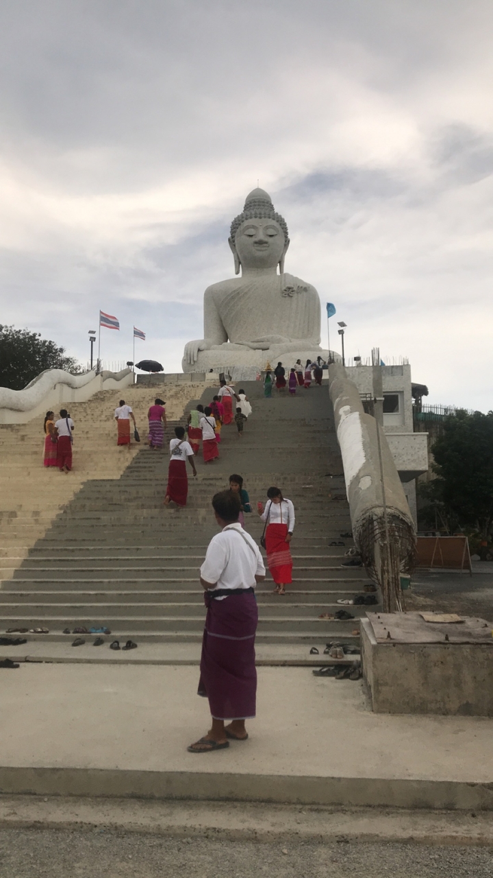 Des gens qui montent les marches vers une grande statue blanche.