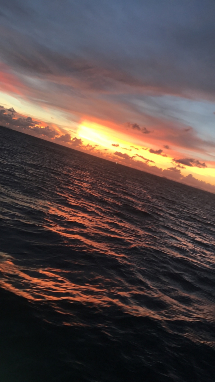 Coucher de soleil sur l'océan avec des reflets colorés sur l'eau.