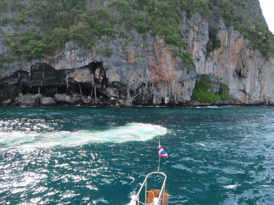 Vue panoramique de l'océan et des falaises avec un drapeau thaïlandais visible.