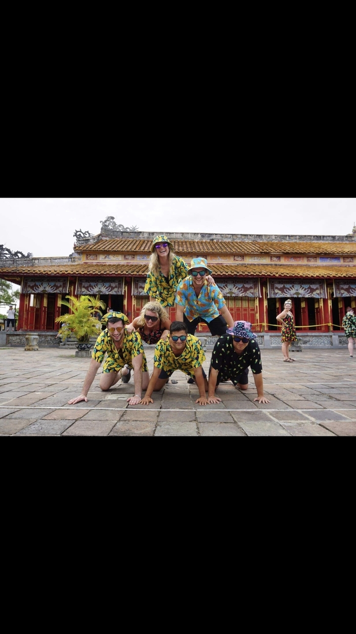 Groupe de touristes en tenues colorées posant devant un bâtiment historique.