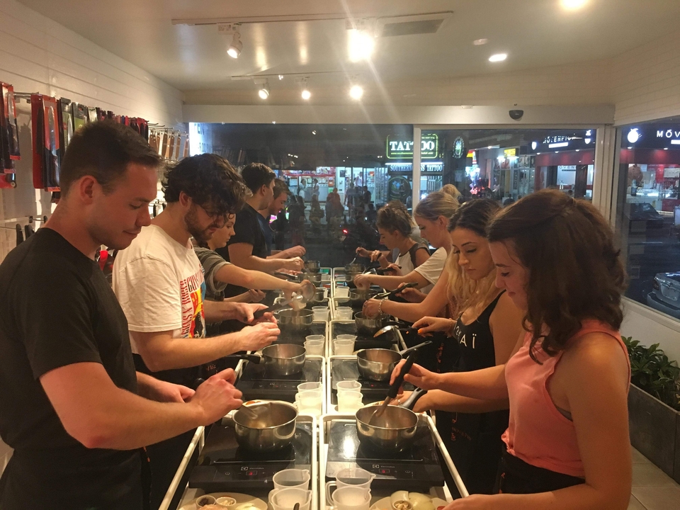 People participating in a cooking class, preparing food at a counter.
**French translation:**
Des personnes participant à un cours de cuisine, préparant de la nourriture sur un comptoir.