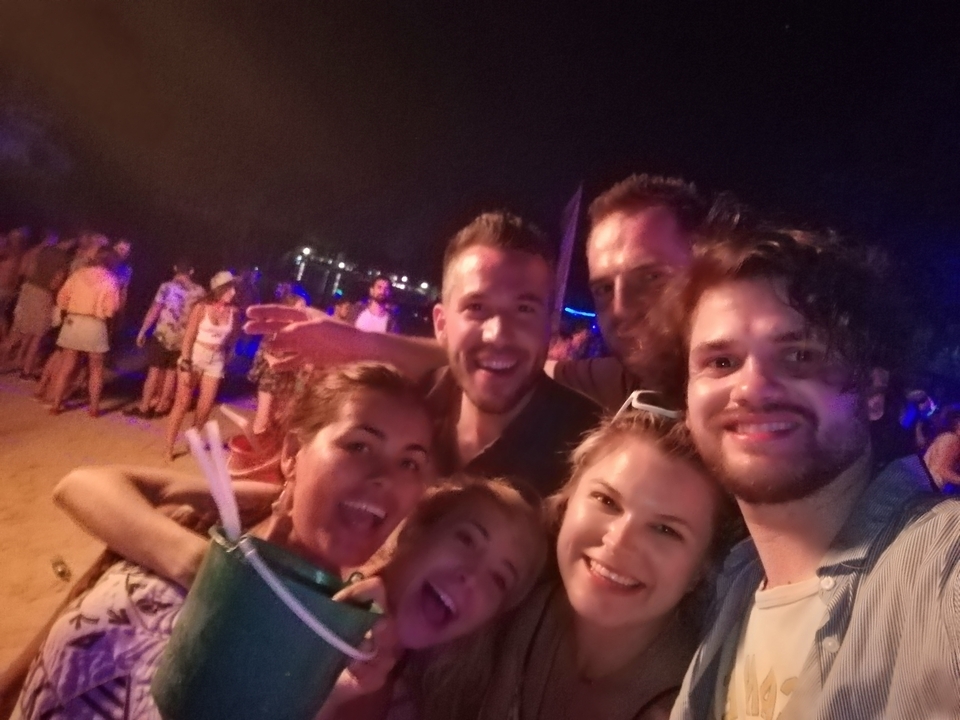 Amis lors d'un rassemblement nocturne sur la plage, souriant pour un selfie.