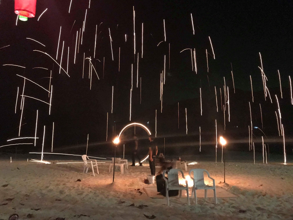 Photo floue d'artistes du feu sur une plage avec des traînées de lumière.