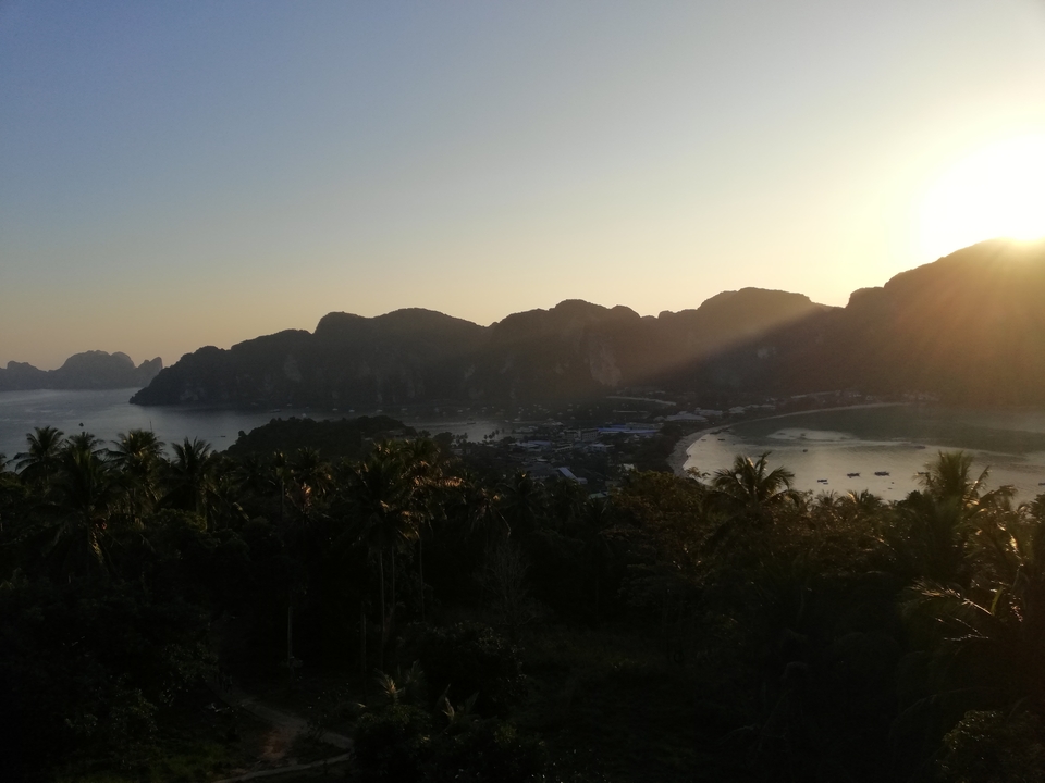 Vue du coucher de soleil sur une baie avec des montagnes et une plage.
