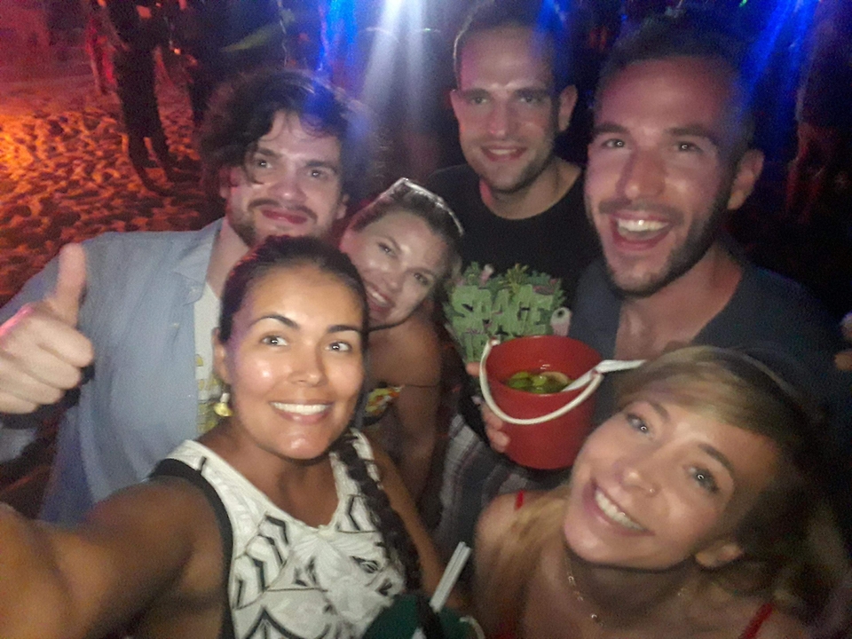 Selfie de groupe d'amis à une fête sur la plage, l'un tenant un seau à boissons.