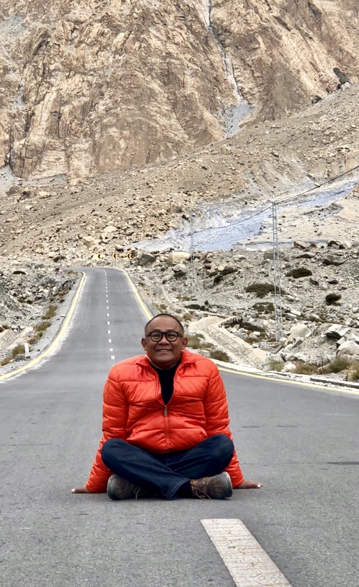 Homme debout sur une route dans un paysage montagneux.