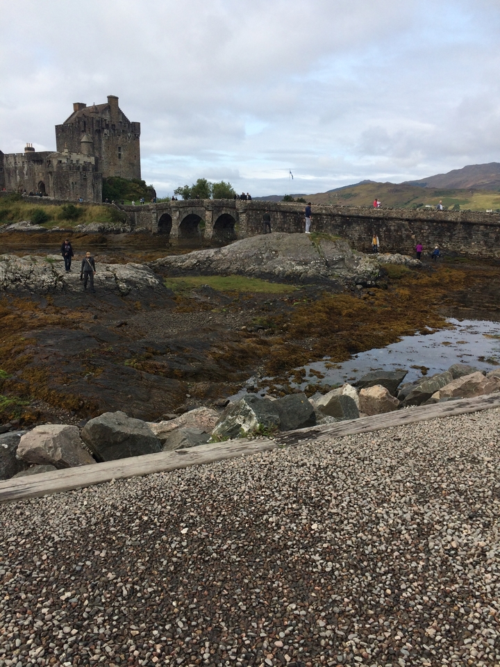 Pont de pierre au-dessus d'une zone rocheuse et remplie d'eau avec des gens qui explorent.