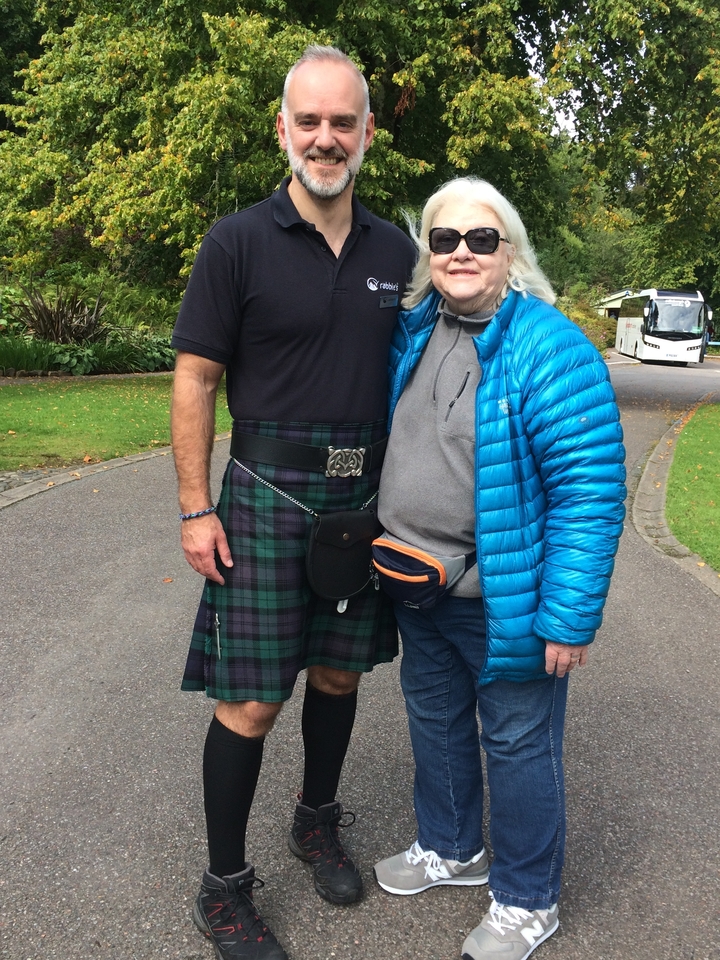 Deux personnes debout, l'une vêtue d'un costume traditionnel écossais.