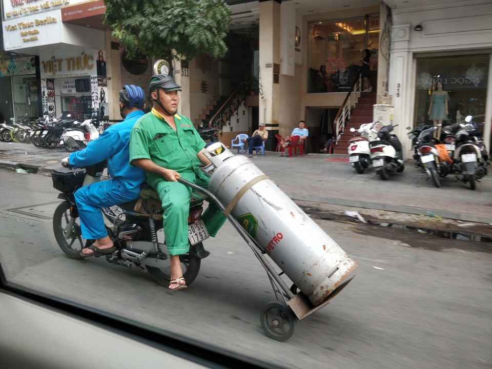 Des personnes sur une moto transportant un grand cylindre.
