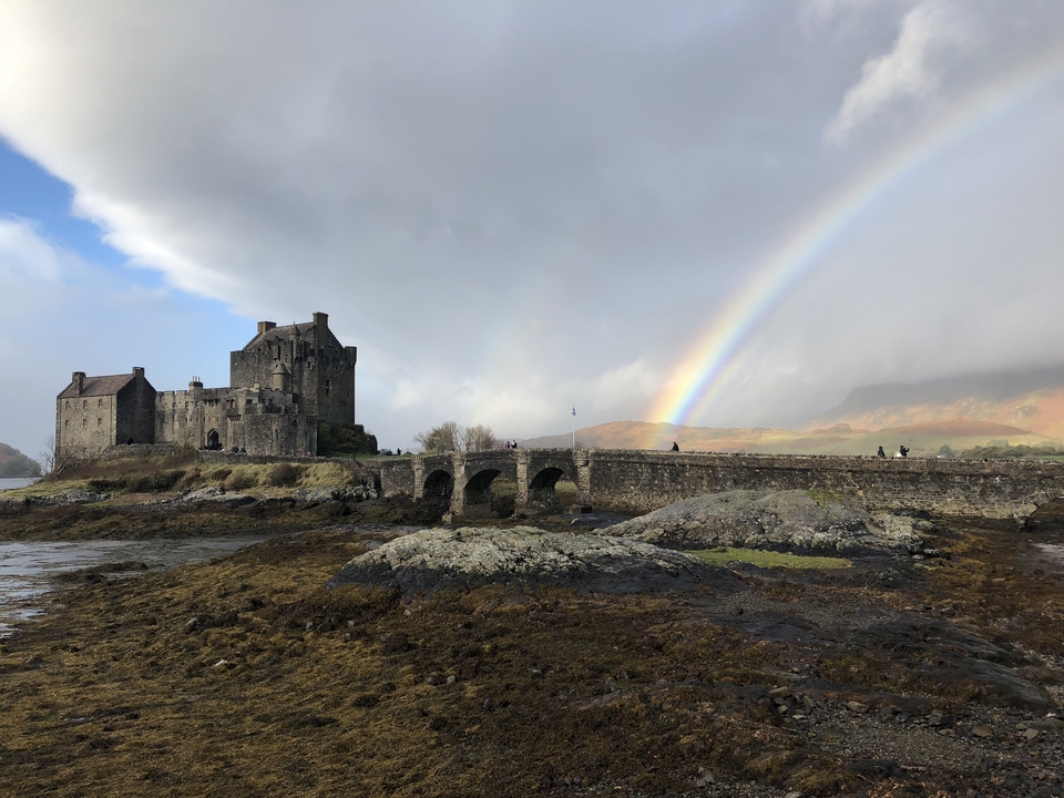 Château de pierre et pont avec un arc-en-ciel dans le ciel.