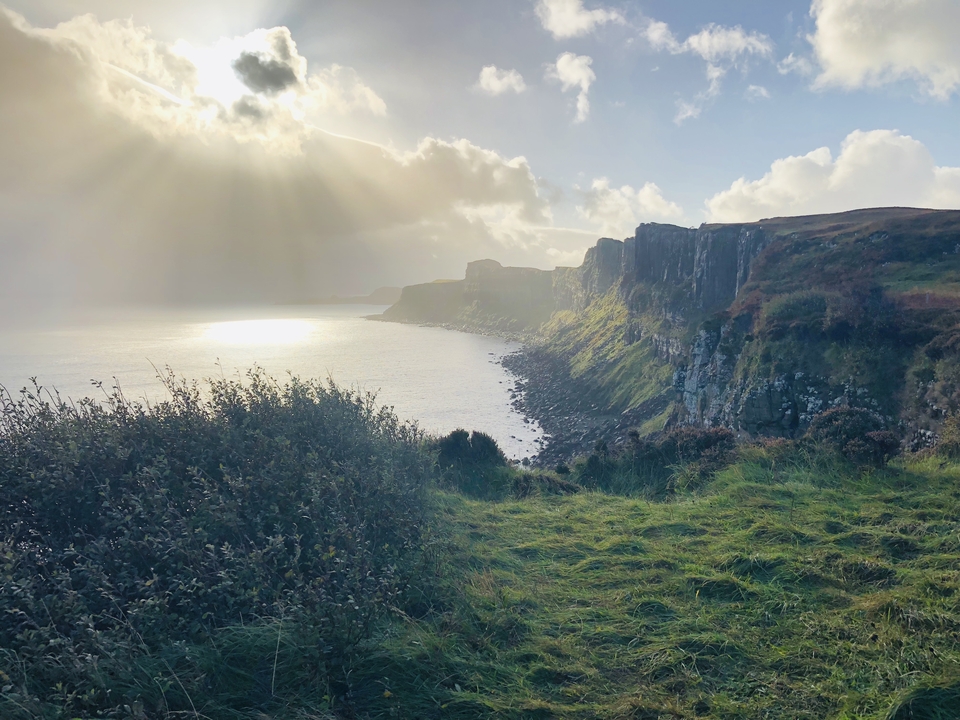 Vue panoramique d'un littoral avec des falaises et un ciel dramatique.
