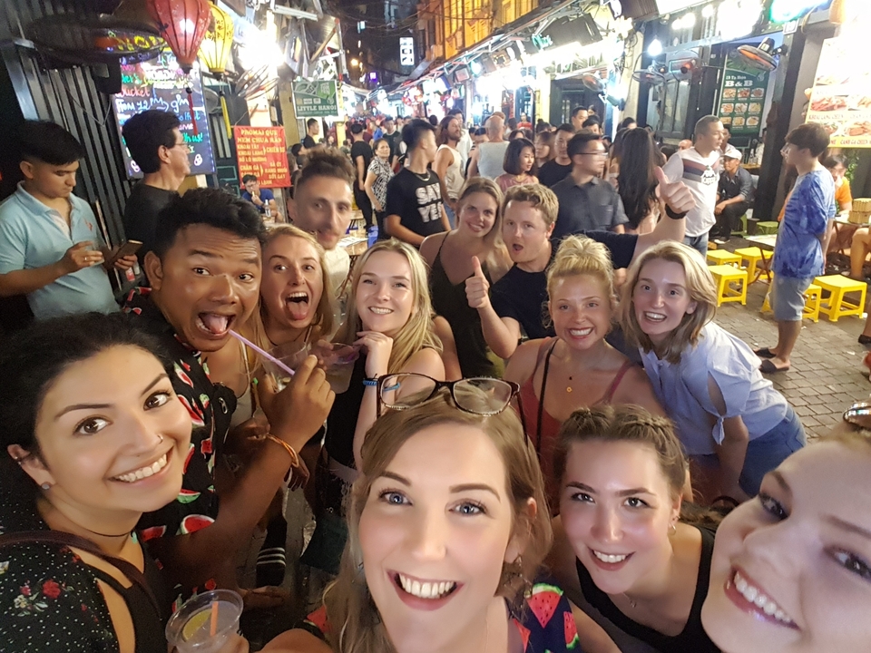 Groupe de personnes profitant d'une sortie nocturne dans une rue animée.