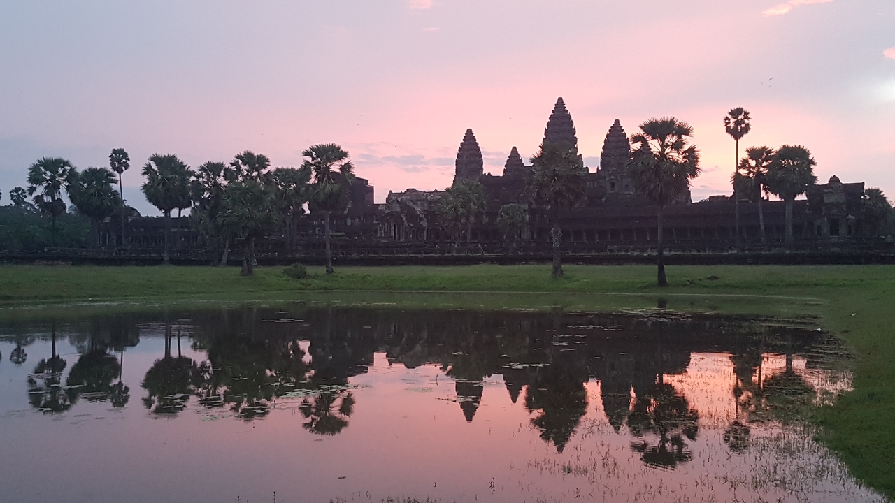 Silhouette de complexe de temples au lever du soleil avec reflet dans l'eau.