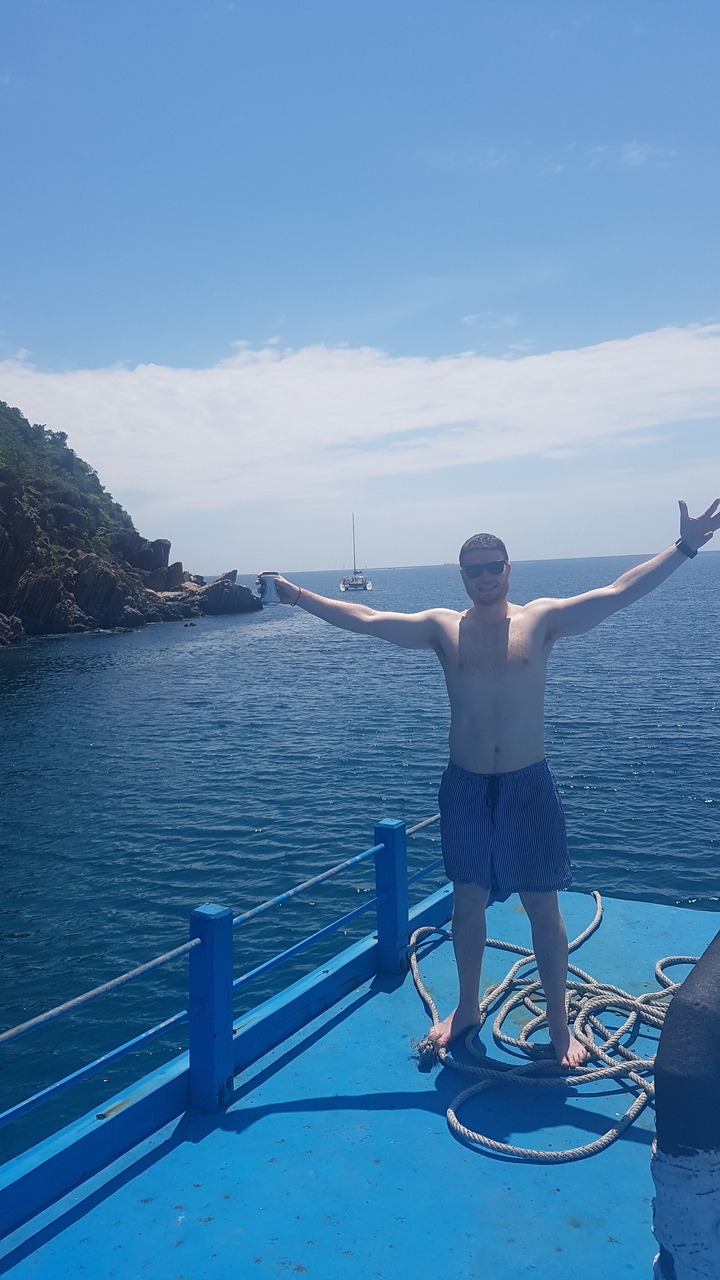 Personne sur un bateau avec les bras étendus en mer.