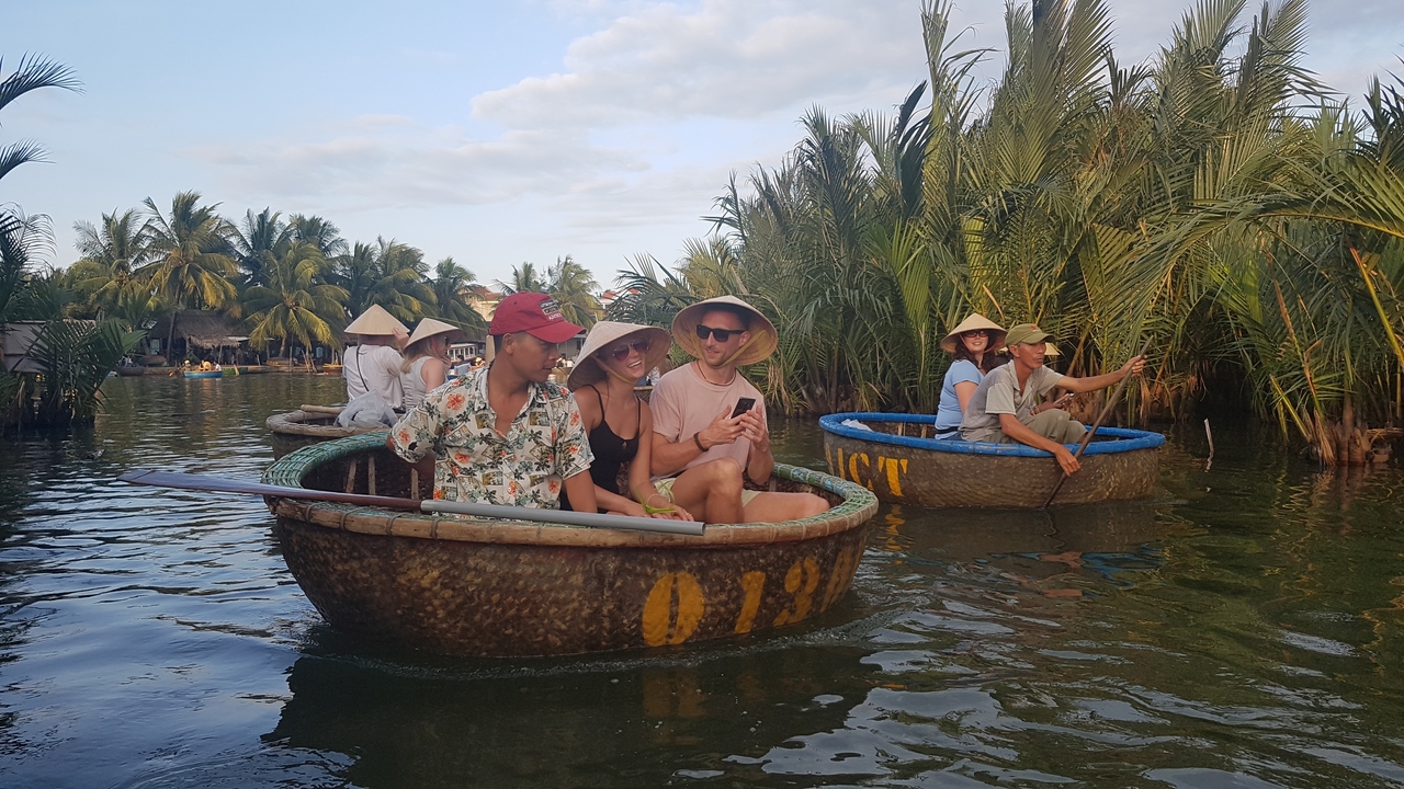 Groupe de personnes dans des bateaux traditionnels sur une rivière entourée d'une végétation luxuriante.