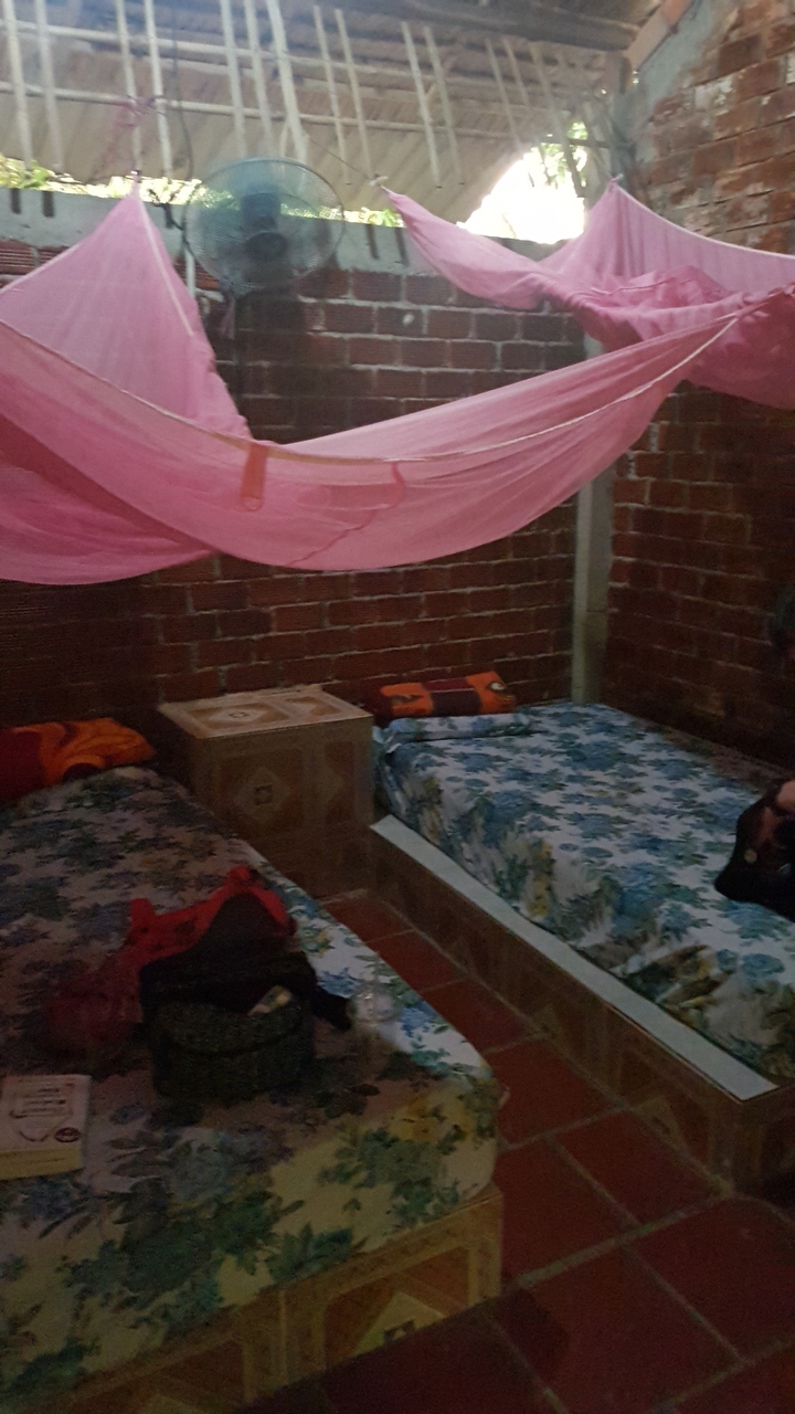 Intérieur d'une chambre simple avec des murs en brique et deux lits.