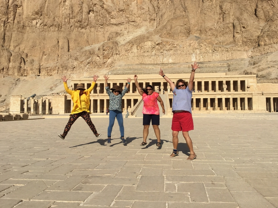 Quatre personnes sautant joyeusement devant la façade d'un temple historique.