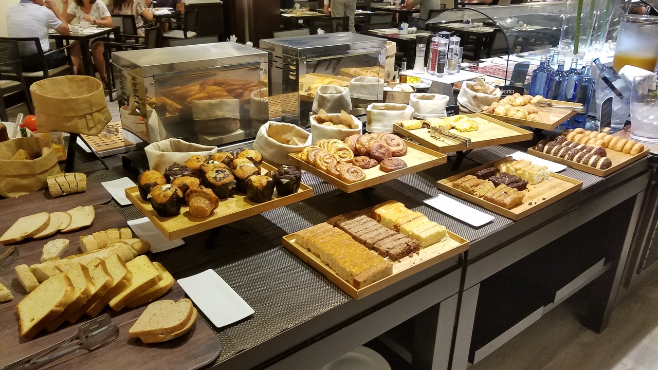 Présentation de divers pains et pâtisseries sur une table de buffet.