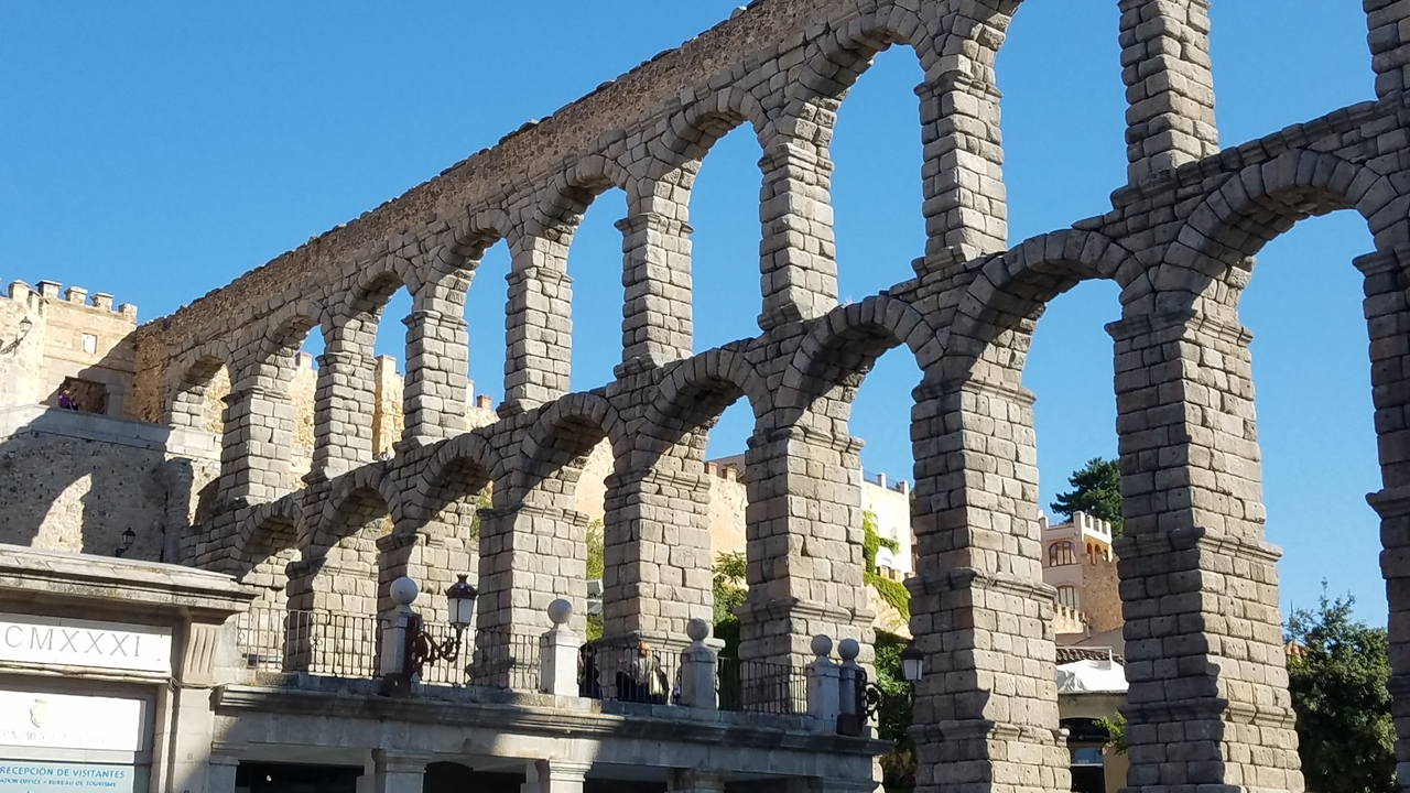 Aqueduc ancien en pierre avec des arches et un ciel bleu dégagé.