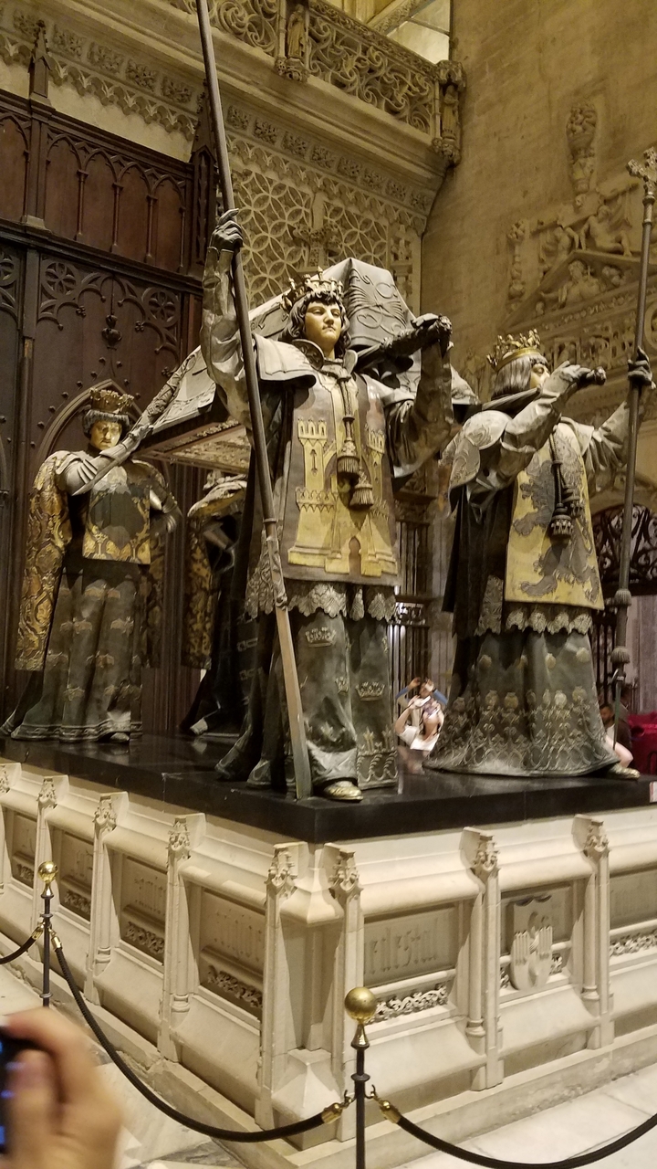 Des statues vêtues de tenues élaborées avec des personnes en arrière-plan.