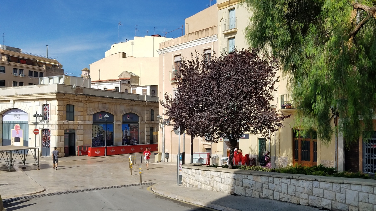 Scène urbaine avec des bâtiments traditionnels et modernes sous un ciel ensoleillé.