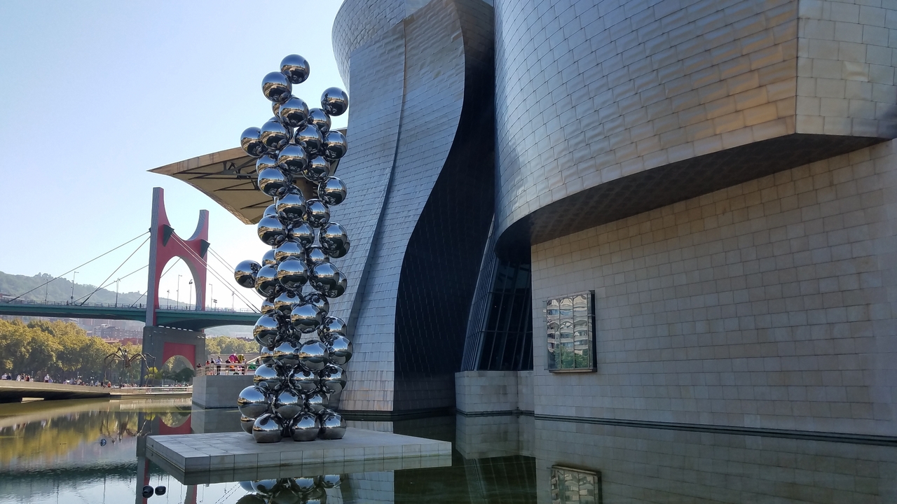 Sculpture d'art moderne devant un bâtiment à l'architecture unique.