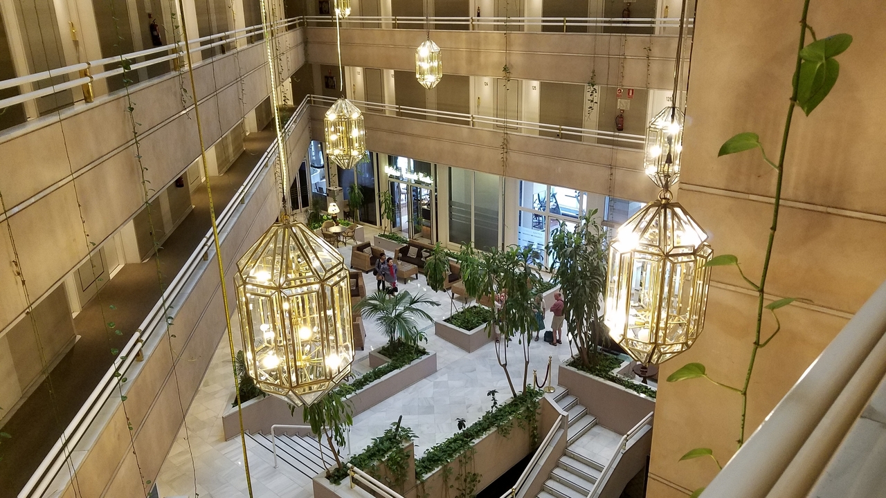 Intérieur d'un bâtiment moderne avec de grandes lampes suspendues et des plantes vertes.