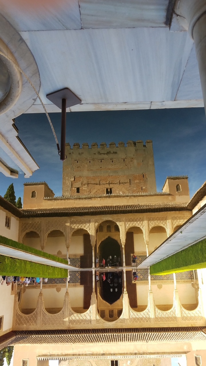 L'Alhambra avec ses arches ornementées et une tour contre un ciel bleu.