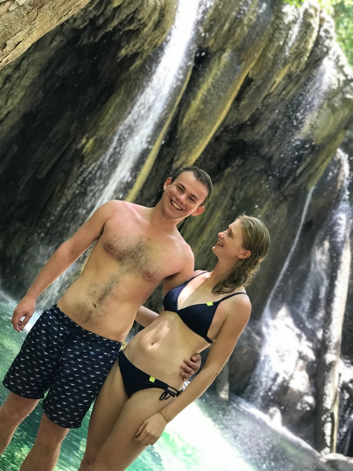 Couple smiling in front of a waterfall.