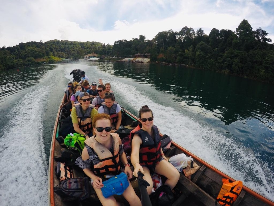 People on a speedboat on a river with lush surroundings.