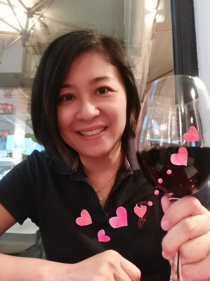 Personne tenant un verre de vin avec des décorations en forme de cœur.