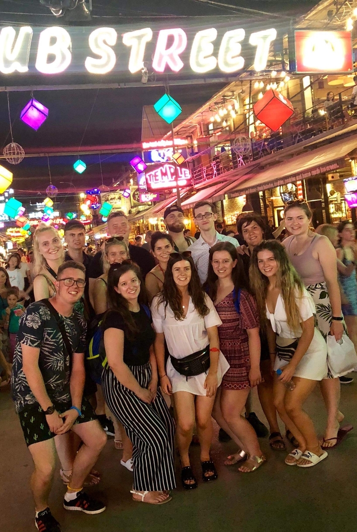 Groupe de personnes posant dans une rue animée la nuit.