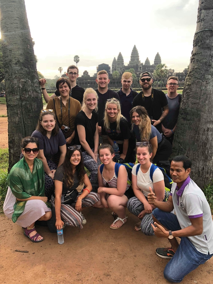 Groupe de personnes posant avec des palmiers en arrière-plan.